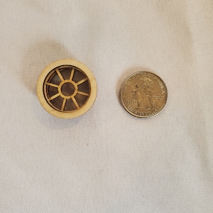 May include: A small wooden window frame with a circular design. The frame is about the size of a US quarter.