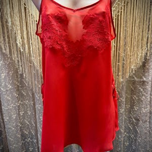 May include: A red sheer slip dress with delicate lace detailing on the bodice.