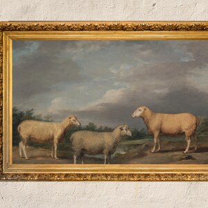May include: A framed oil painting depicting three sheep in a field. The sheep are white and brown, and the field is green with a cloudy sky in the background.