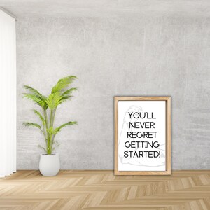 May include: A motivational quote in a framed print with a white background and a wood frame. The quote reads "You'll never regret getting started!" with a stylized arm flexing in the background.