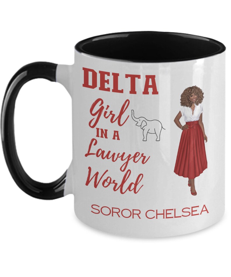 May include: White ceramic coffee mug with a black handle and black rim. The mug has a red graphic that says "DELTA Girl in a Lawyer World" with a small elephant illustration. The graphic also includes the text "SOROR CHELSEA".