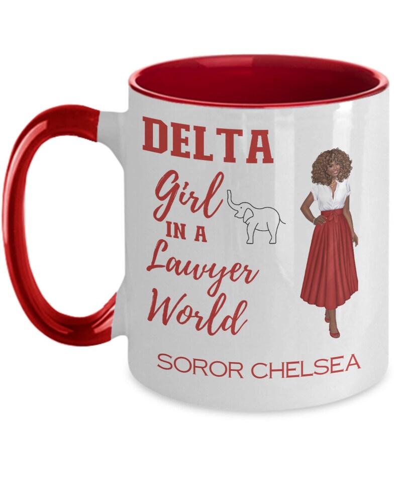 May include: White ceramic mug with a red rim and handle. The mug features a red graphic of a woman in a red skirt and a white elephant. The text on the mug reads "DELTA Girl in a Lawyer World SOROR CHELSEA".
