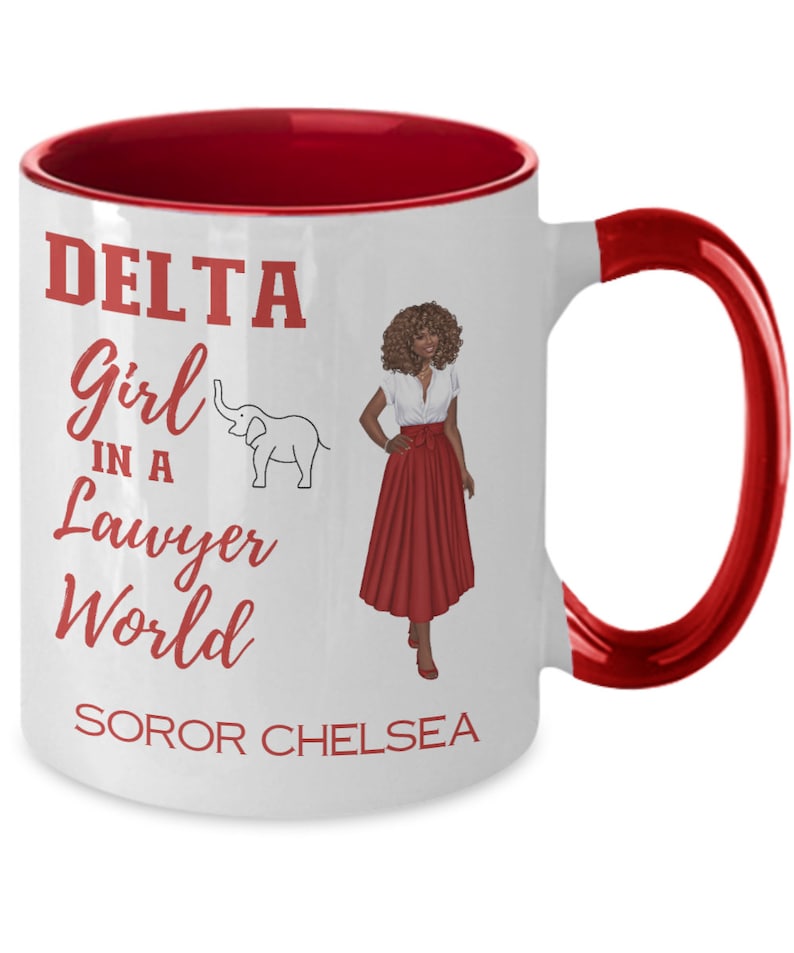 May include: White ceramic coffee mug with a red rim and handle. The mug features a red graphic of a woman in a red skirt and a white top, with the text "DELTA Girl in a Lawyer World SOROR CHELSEA".