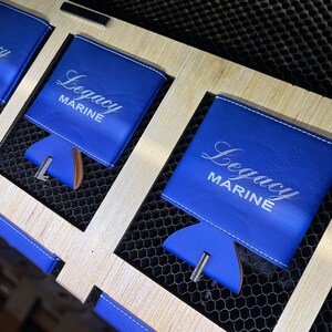 May include: Three blue leather can coolers with white stitching and the text "Legacy Marine" in white lettering.