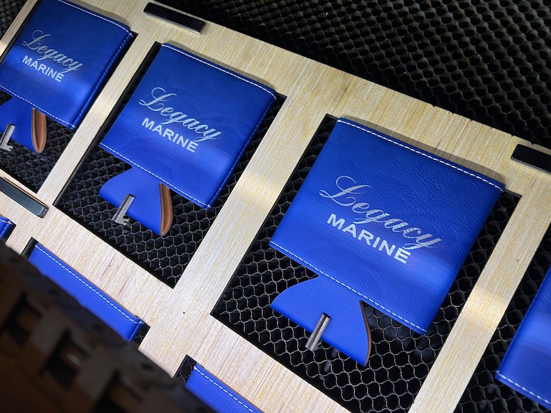 May include: Three blue leather can coolers with white stitching and the text "Legacy Marine" in white lettering.