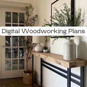 Puede incluir: Una consola de madera con patas de metal negro. La mesa mide 122 cm de largo y 41 cm de ancho. La mesa está decorada con un jarrón de vegetación, una lámpara y una pequeña planta en maceta.