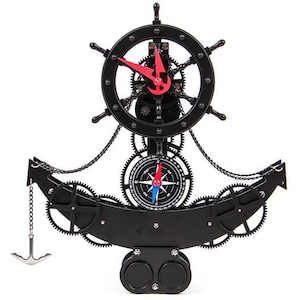 Può includere: Orologio nero a tema nautico a forma di ancora, con un timone in alto e una bussola al centro. L'orologio ha lancette rosse e ingranaggi visibili. Una piccola ancora è appesa a una catena.