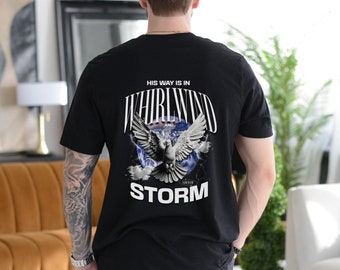 Op de afbeelding: Zwart T-shirt met een grafische print van een duif die door een wervelwind en een storm vliegt. De tekst "His way is in whirlwind and storm" staat op het shirt gedrukt.