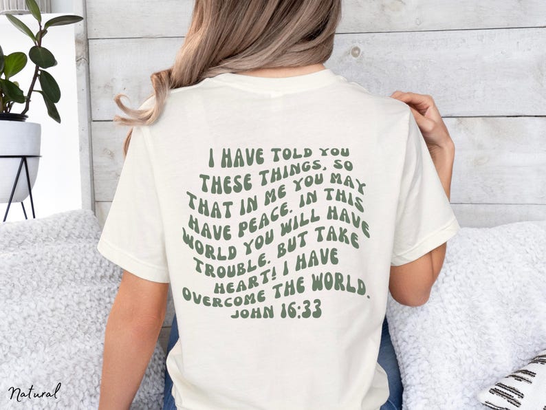 May include: A white t-shirt with a green text graphic that reads "I have told you these things, so that in me you may have peace. In this world you will have trouble. But take heart! I have overcome the world. John 16:33"