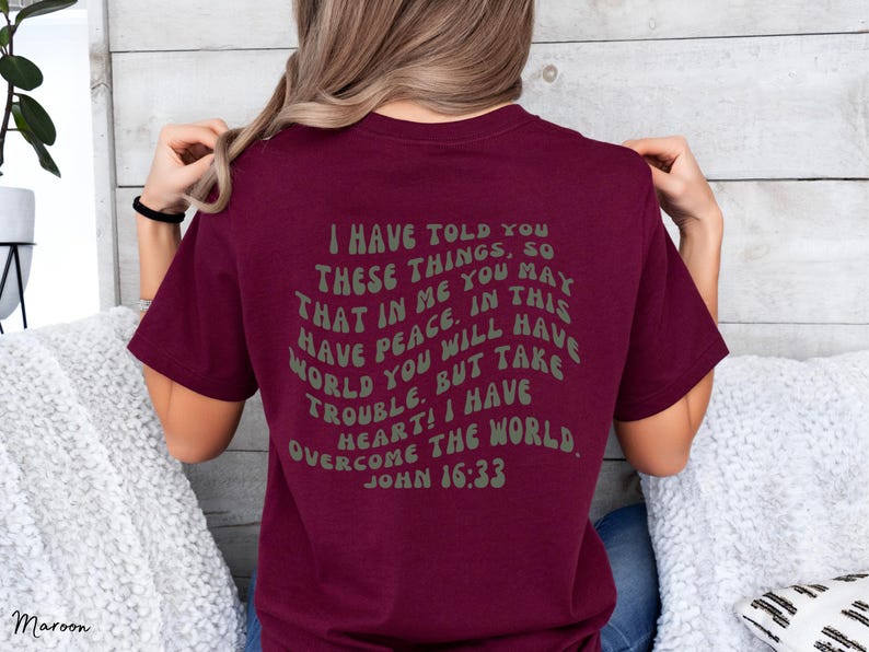 May include: Maroon t-shirt with a white text graphic that reads "I have told you these things, so that in me you may have peace. In this world you will have trouble. But take heart! I have overcome the world. John 16:33"