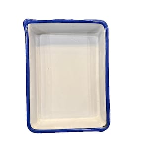 May include: A rectangular ceramic dish with a white interior and a vibrant blue border. The dish has a simple, clean design, perfect for serving or displaying small items. The blue border adds a pop of color to the otherwise neutral piece.
