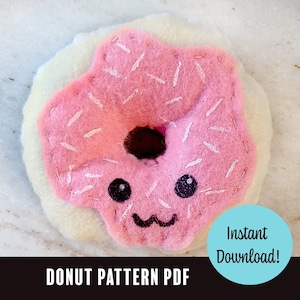 May include: A pink felt donut with white sprinkles and a cute face. The donut has a brown center and is surrounded by a white felt ring. The text "DONUT PATTERN PDF" and "Instant Download!" is visible in the image.