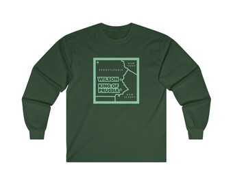 Puede incluir: Una camiseta de manga larga verde oscuro con un contorno verde claro del estado de Pensilvania y el texto "WILSON KING OF PRUSSIA" dentro del contorno.