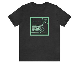 Puede incluir: Una camiseta gris oscuro jaspeada con un contorno verde del estado de Pensilvania y el texto "WILSON KING OF PRUSSIA" dentro del contorno.