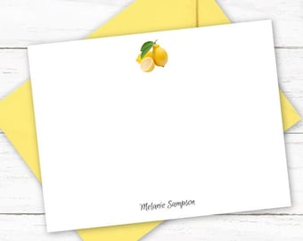 May include: White stationery set featuring a lemon illustration. Includes a white card with a lemon graphic, a yellow envelope, and a silver pen. The name "Melanie Sampson" is printed on the card. The stationery is from Big Dog Paper Co.