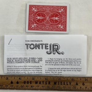 May include: A red playing card deck with a white plastic sleeve, and a folded instruction sheet. The text on the sheet reads "TON ONOSAKA'S TONTE JR." and describes a jumbo card trick. A ruler is at the bottom.
