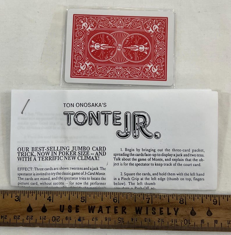 May include: A red playing card deck with a white plastic sleeve, and a folded instruction sheet. The text on the sheet reads "TON ONOSAKA'S TONTE JR." and describes a jumbo card trick. A ruler is at the bottom.