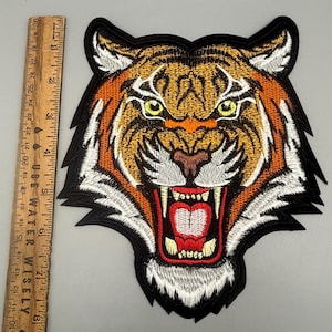 May include: Embroidered tiger head patch with orange, brown, and white details, featuring an open mouth with red and white teeth. The patch is approximately 8 inches wide and 8 inches tall.