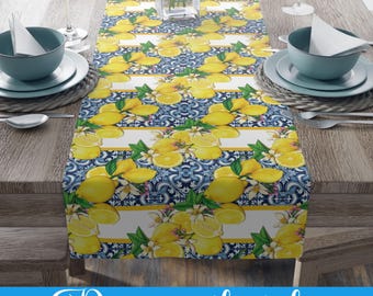 May include: A table runner with a lemon and floral pattern. The design features yellow lemons and white flowers on a blue and white background. The text "Decor with style" is at the bottom of the image.