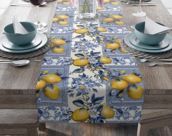 May include: A blue and white table runner with a lemon and floral pattern. The runner is on a wooden table with place settings.