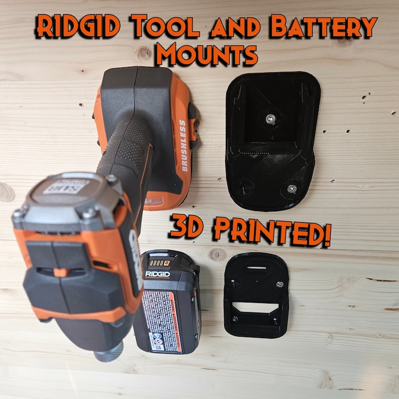 Pu&ograve; includere: Un supporto da parete stampato in 3D per un trapano e una batteria senza fili Ridgid. Il supporto &egrave; nero e ha un design semplice. Il testo "3D PRINTED!" &egrave; scritto in lettere arancioni su sfondo bianco.