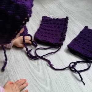 Könnte beinhalten: Ein Set aus drei lila gehäkelten Mützen mit Bändern. Die Mützen sind mit einem strukturierten Stich gearbeitet und haben ein schlichtes Design.