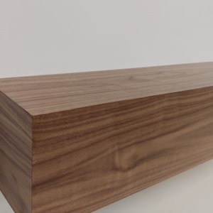 May include: A long, rectangular wooden shelf with a natural wood finish. The shelf is made of solid wood and has a smooth, polished surface.