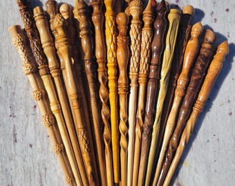 May include: A collection of handcrafted wooden wands arranged in a fan shape. Each wand features distinct wood grains, varying shades of brown, and unique carved details including spiral patterns, textured grips, and smooth, tapered shafts.