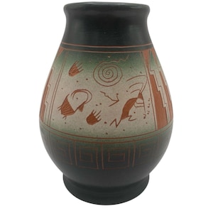 Könnte beinhalten: Eine bauchige Keramikvase mit mattem schwarzem Finish an der Öffnung und am Boden. Die Mitte zeigt ein hellbeiges Band, das mit rotbraunen, handgemalten petroglyphenartigen Figuren, Spiralen und geometrischen Mustern auf grünem Verlauf verziert ist.