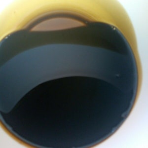 Może przedstawiać: Zbliżenie na biały ceramiczny kubek wypełniony czarną kawą. Kawa ma ciemnobrązową obw&oacute;dkę wok&oacute;ł krawędzi kubka.