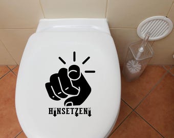 May include: A white toilet bowl with a black decal of a pointing hand and the text "HINSETZEN".