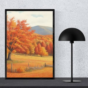 Könnte beinhalten: Gerahmter Kunstdruck mit einer Herbstlandschaft. Das Kunstwerk zeigt orange und gelbe Bäume, einen Holzzaun und einen Berg im Hintergrund. Rechts befindet sich eine schwarze Lampe mit einem halbkugelförmigen Schirm.