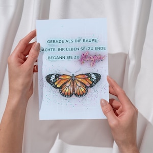 Könnte beinhalten: Eine Grußkarte mit einer Illustration eines orange-schwarzen Schmetterlings. Die Karte enthält deutschen Text, der lautet: "GERADE ALS DIE RAUPE DACHTE, IHR LEBEN SEI ZU ENDE BEGANN SIE ZU fliegen."