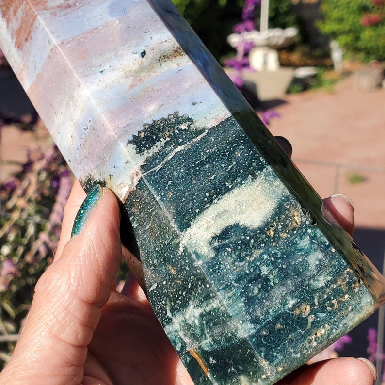 May include: A polished stone tower with a hexagonal shape, featuring a distinct color transition from a deep, mossy forest green at the base to a lighter, translucent lavender and cream-colored banding toward the top, with visible mineral inclusions.