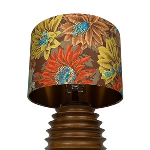 May include: A brown wooden table lamp with a floral patterned lampshade. The lampshade has a brown background with red, yellow, and blue flowers.