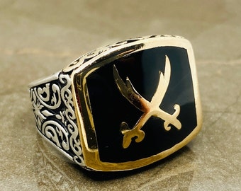 May include: A silver ring with a black onyx stone and a gold-colored sword design.