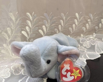 May include: A light blue plush elephant toy with a red heart-shaped tag that says "Beanie Babies".