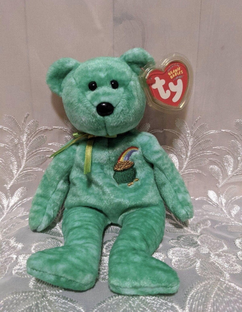 Peut inclure: Ours en peluche vert Beanie Baby avec un arc-en-ciel et un pot d'or brod&eacute;s sur sa poitrine. L'ours a une &eacute;tiquette Ty attach&eacute;e &agrave; son oreille qui dit "Beanie Babies" et "ty".