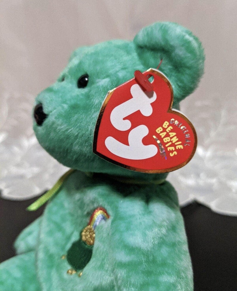 Peut inclure: Ours en peluche vert Beanie Baby avec un arc-en-ciel et un pot d'or brod&eacute;s sur sa poitrine. L'ours en peluche a une &eacute;tiquette Ty attach&eacute;e &agrave; son oreille qui indique "Original Beanie Babies".