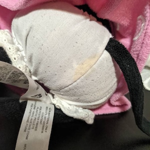 May include: A pink and black plush toy with a white fabric lining. The toy has a tag attached that reads "NEW MATERIAL ONLY REG.NO 057-02250916 CONTENT POLYESTER FIBRES PLASTIC PELLETS HYLENE VINYL ACETATE FOAM POLYURETHANE FOAM MAT&Eacute;RIAUX NE NDE PERMI CON FIBRES DE MOUSSE STHI L&Ecirc;NE BILLES DE MOUSSE DE PG".