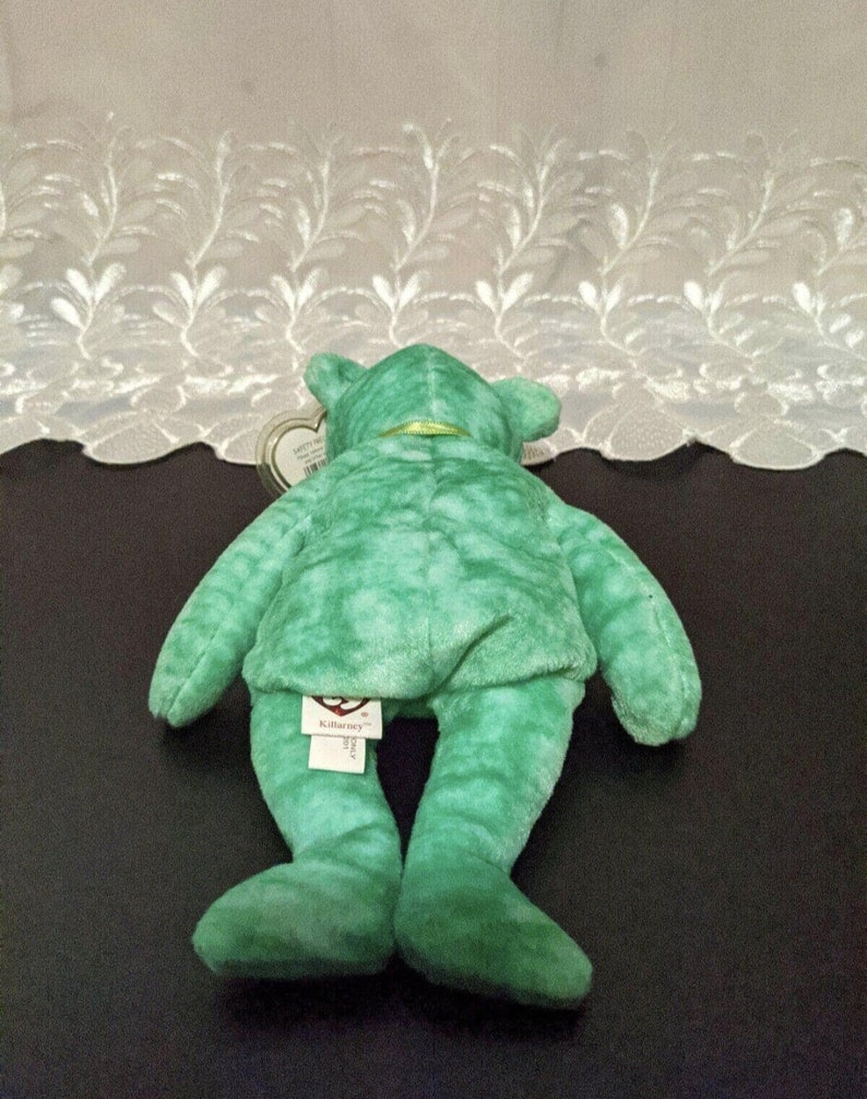 Peut inclure: Ours en peluche Beanie Baby vert tie-dye avec un ruban vert autour du cou. L'ours est couch&eacute; sur le dos, les pattes en l'air. L'ours a une &eacute;tiquette Ty attach&eacute;e &agrave; son pied qui dit "Beanie Babies" et "Ty Inc."