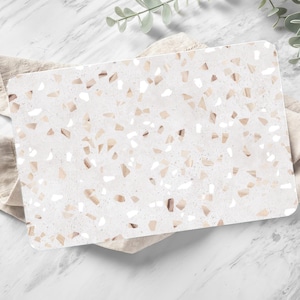 Peut inclure: Un set de table rectangulaire en terrazzo blanc et beige. Le set de table a une surface lisse.