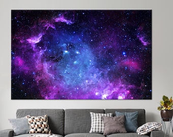 Puede incluir: Una gran impresión en lienzo que presenta una nebulosa vibrante con tonos de púrpura y azul, salpicada de estrellas brillantes sobre un fondo oscuro.