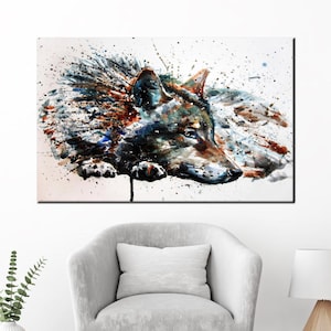May include: Watercolor painting of a wolf's head with a white background and splashes of blue, brown, and black paint.