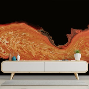 May include: Abstract orange and black wall mural with a flowing, marbled design. The image shows a modern living room with a white cabinet, side tables, and decorative plants. Gold pendant lights hang from the ceiling.