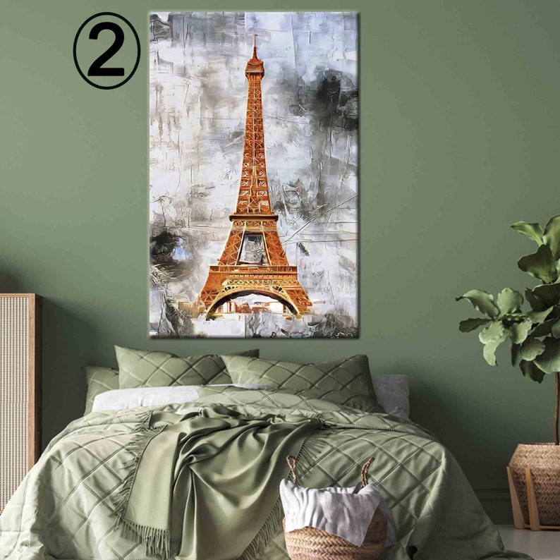 May include: An abstract painting of the Eiffel Tower in shades of orange and brown against a textured gray and white background. The artwork is displayed above a bed with green bedding, creating a decorative interior design element.