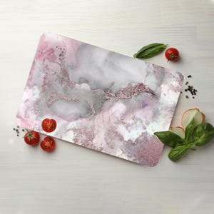 May include: A pink and gray marble-patterned cutting board with a glittery finish. The board is made of durable plastic and is perfect for cutting, serving, and displaying food.