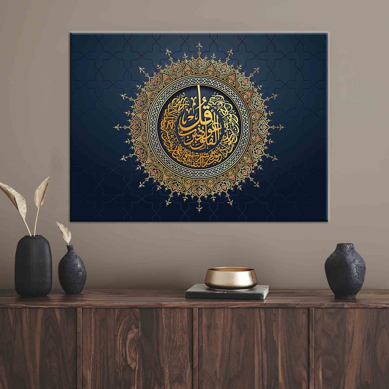 Puede incluir: Una impresi&oacute;n art&iacute;stica en lienzo con caligraf&iacute;a &aacute;rabe dorada dentro de un dise&ntilde;o circular ornamentado. La obra de arte est&aacute; sobre un fondo azul oscuro con un sutil patr&oacute;n geom&eacute;trico. La impresi&oacute;n se muestra sobre un mueble de madera con jarrones decorativos.