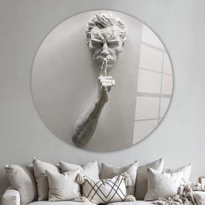 Pu&ograve; includere: Una scultura in gesso bianco di una testa e una mano umane, con la mano alzata alla bocca in un gesto di silenzio. La scultura &egrave; montata su uno sfondo rotondo bianco.