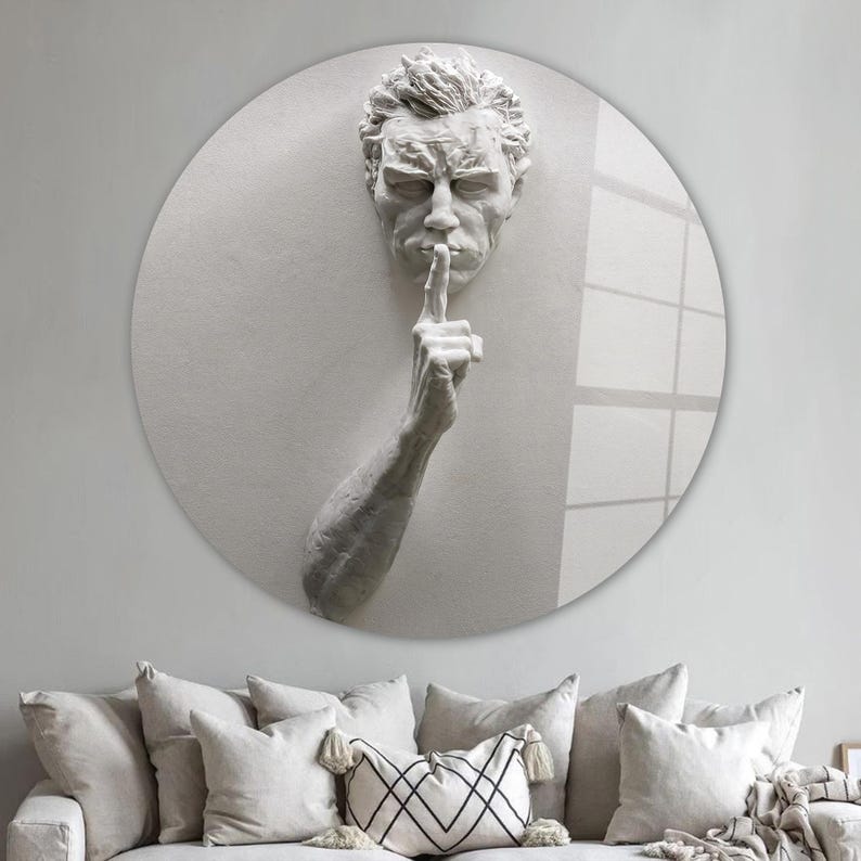 Pu&ograve; includere: Una scultura in gesso bianco di una testa e una mano umane, con la mano alzata alla bocca in un gesto di silenzio. La scultura &egrave; montata su uno sfondo rotondo bianco.